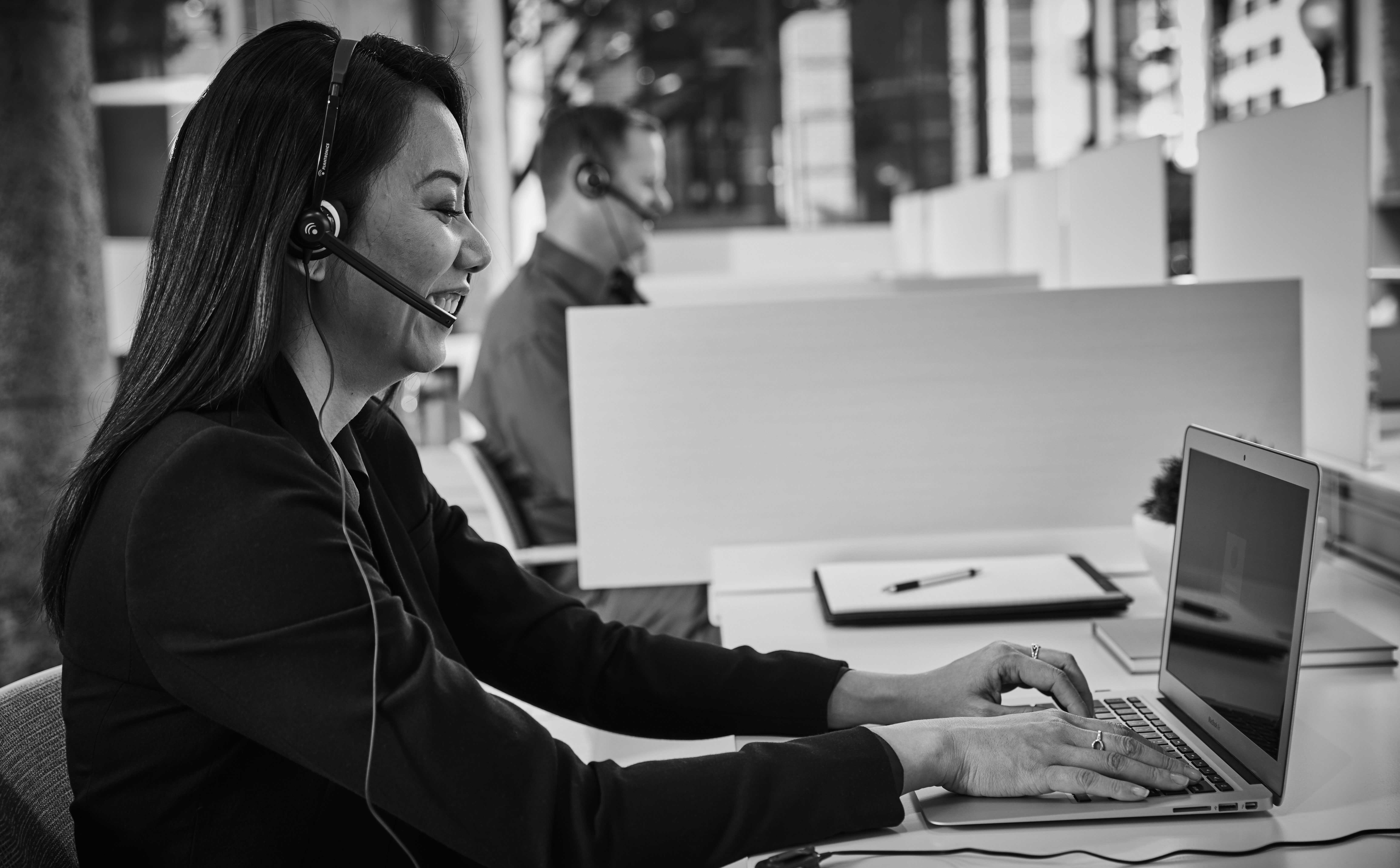 A customer service representative talks on a headset while typing at a computer