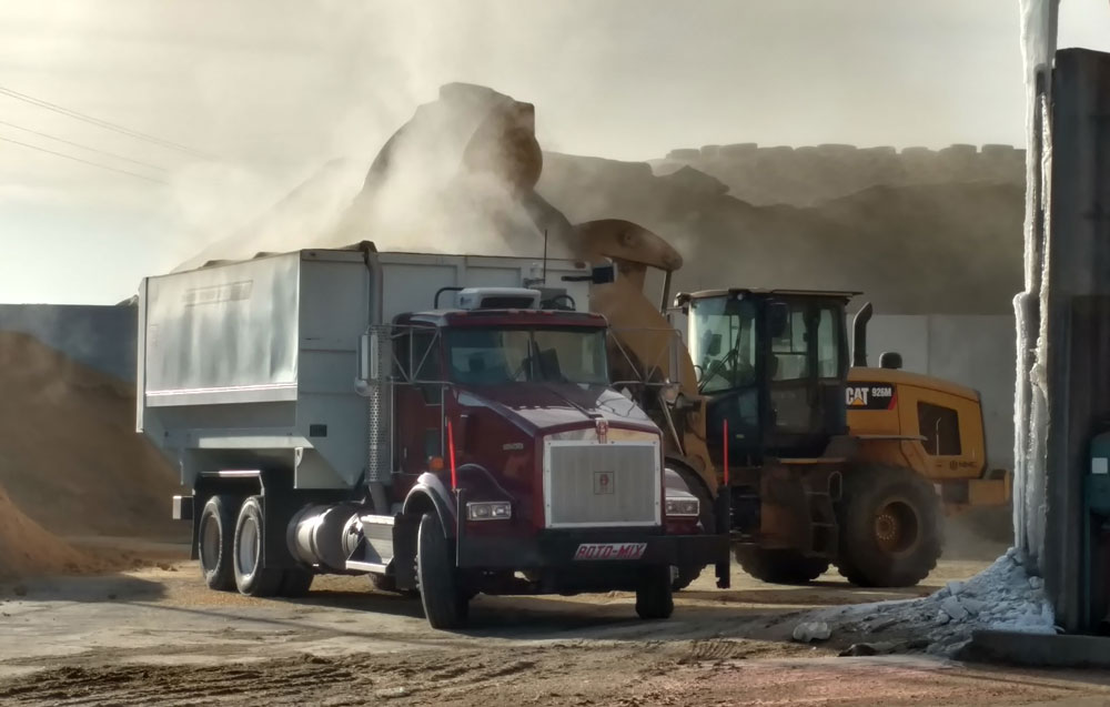 A digger dumps a load into the back of a truck