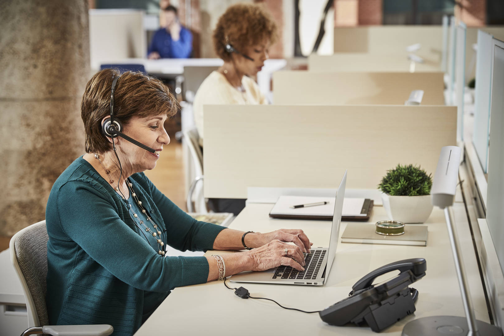 An customer service associate takes calls while working on a laptop