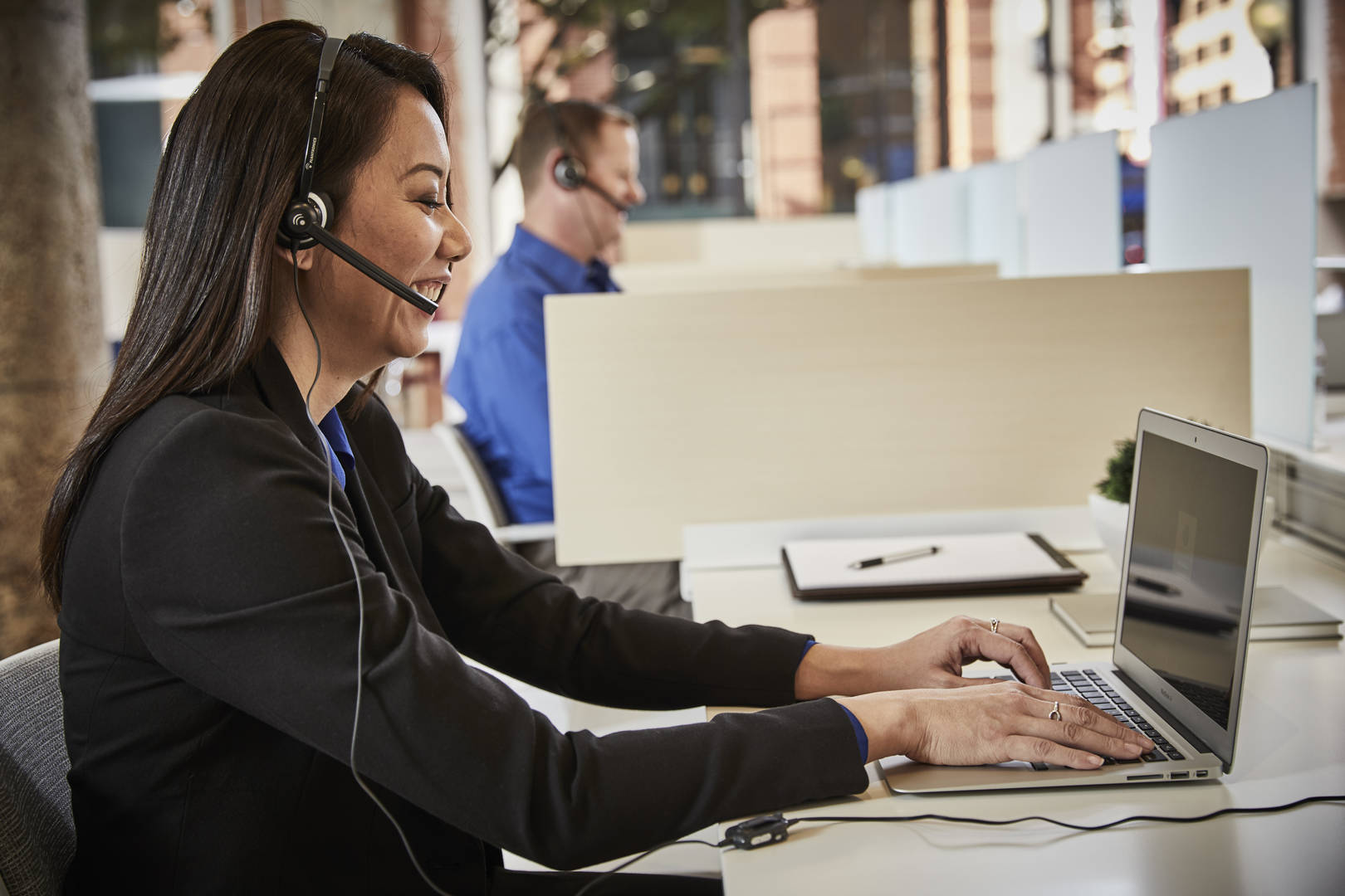 An customer service associate takes calls while working on a laptop