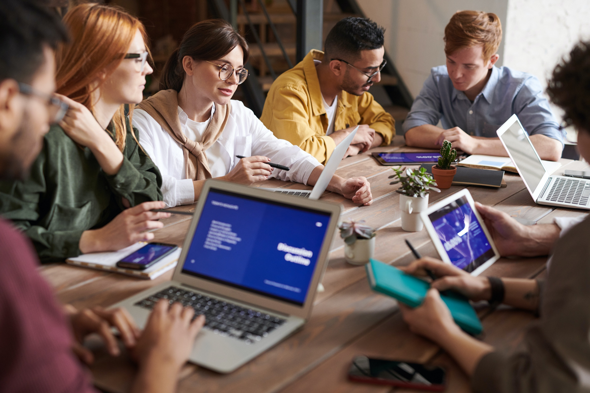 A group of interns sitting around a table and working together on their laptops