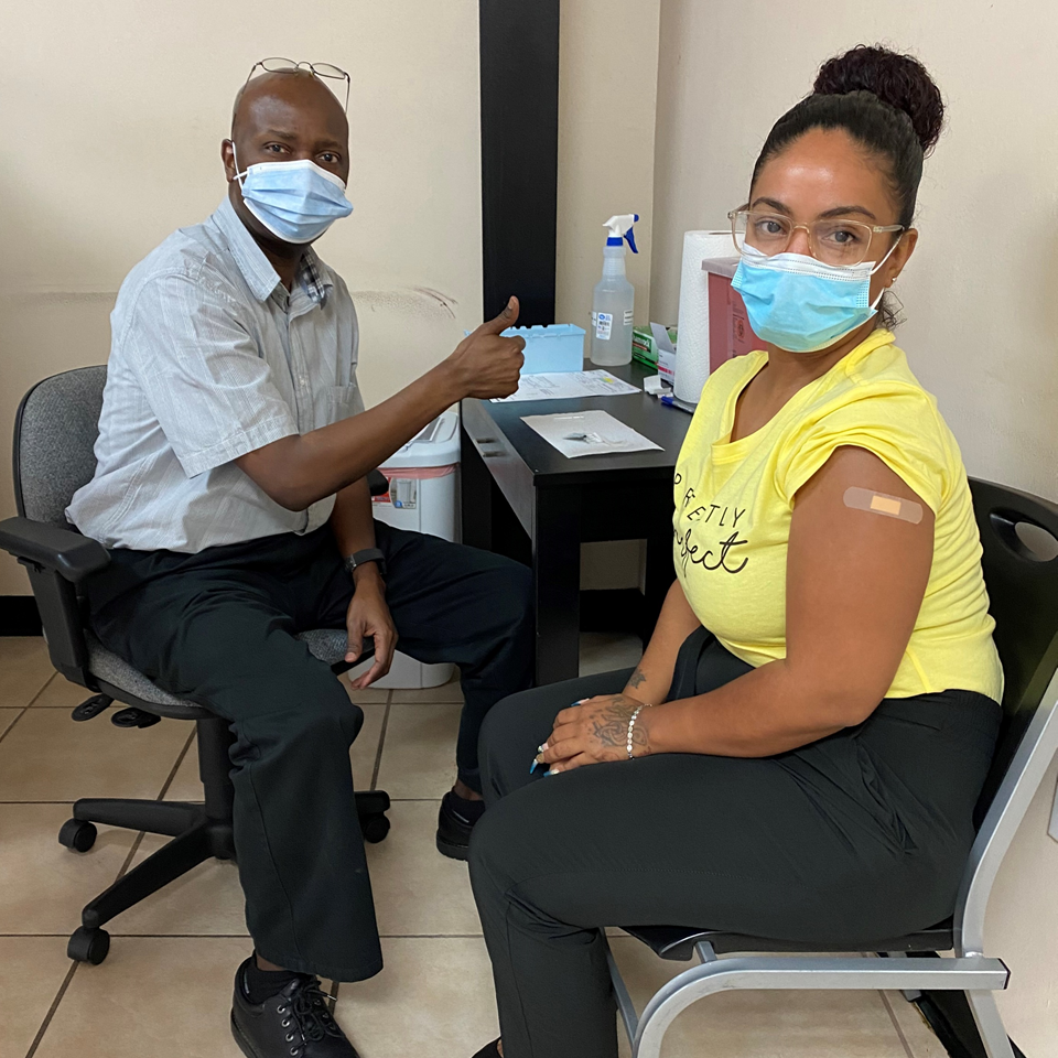 A pharmacist giving a thumbs up after administering COVID-19 vaccine to a patient