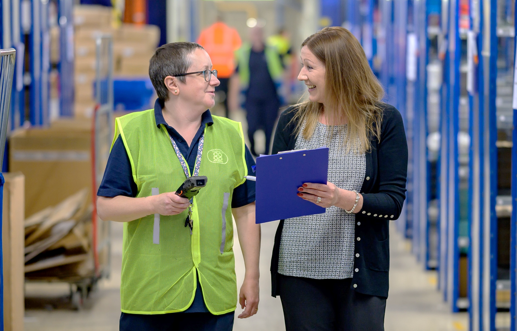 A manager and team member walking and talking in a warehouse
