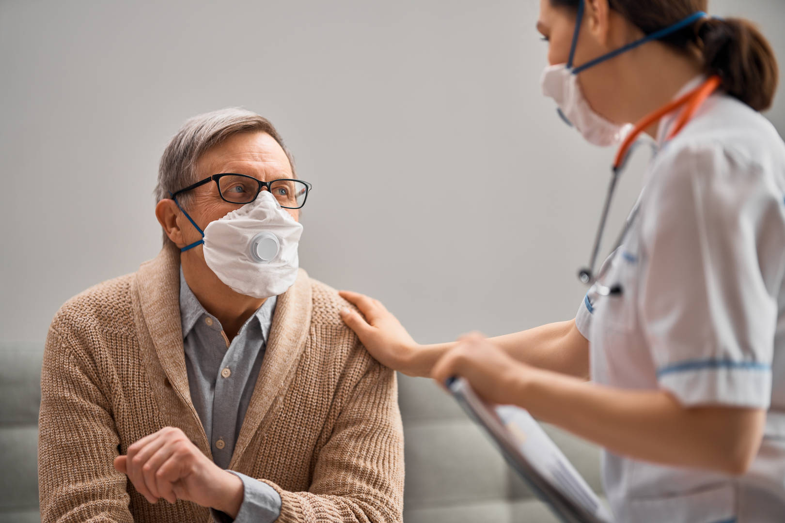 Masked patient and masked nurse in conversation