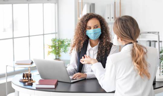 Medical staff wearing masks talking at laptop