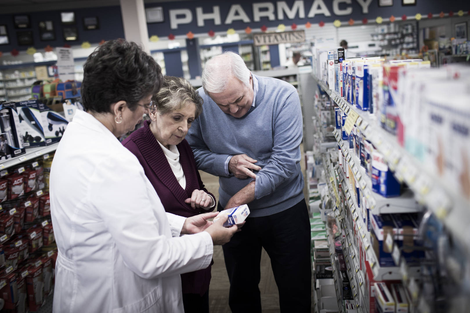 Pharmacist helping couple in aisle