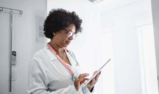 Black female doctor looks at iPad