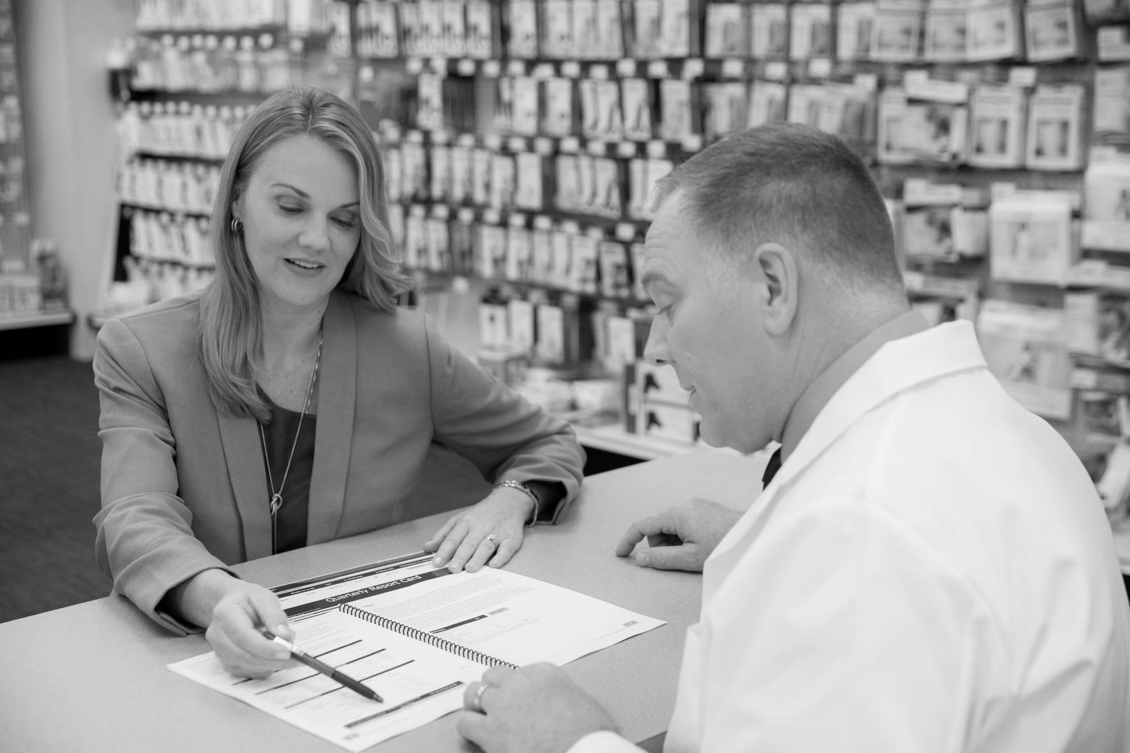 A Good Neighbor Pharmacy business coach reviews performance reports with a pharmacist