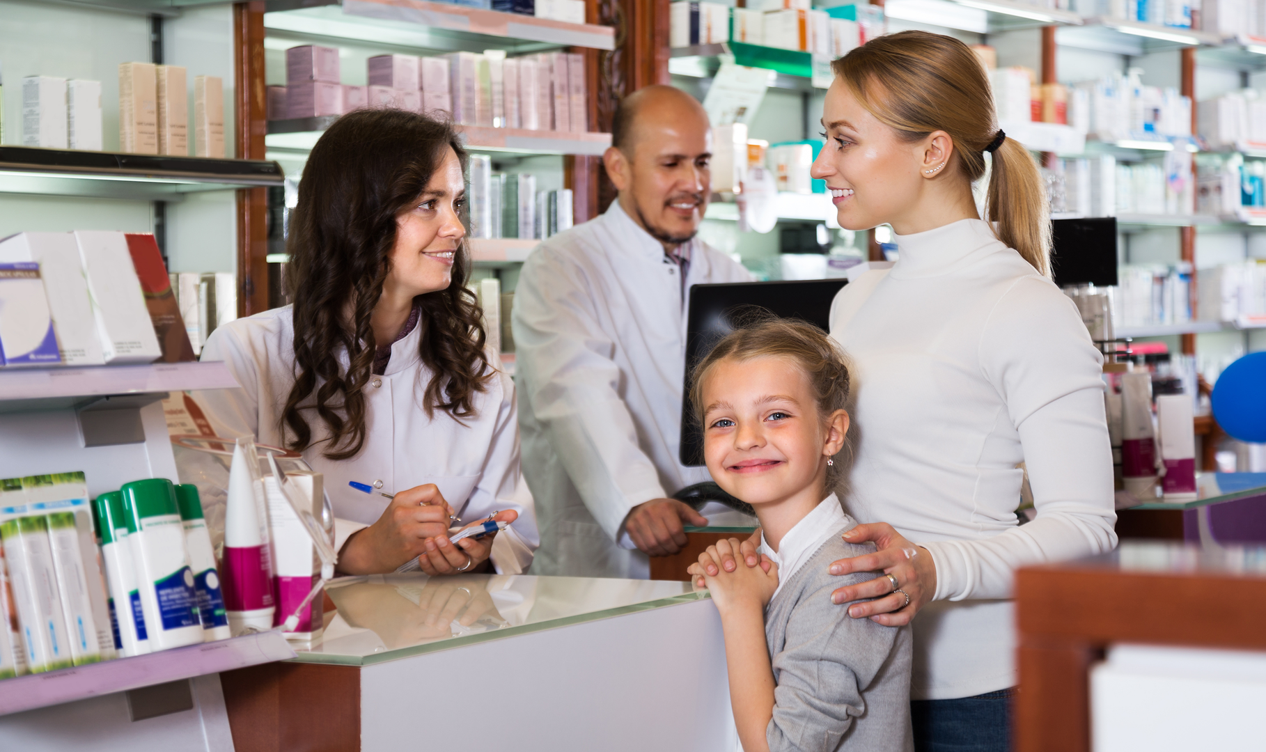 Two pharmacists help a mother and her daughter