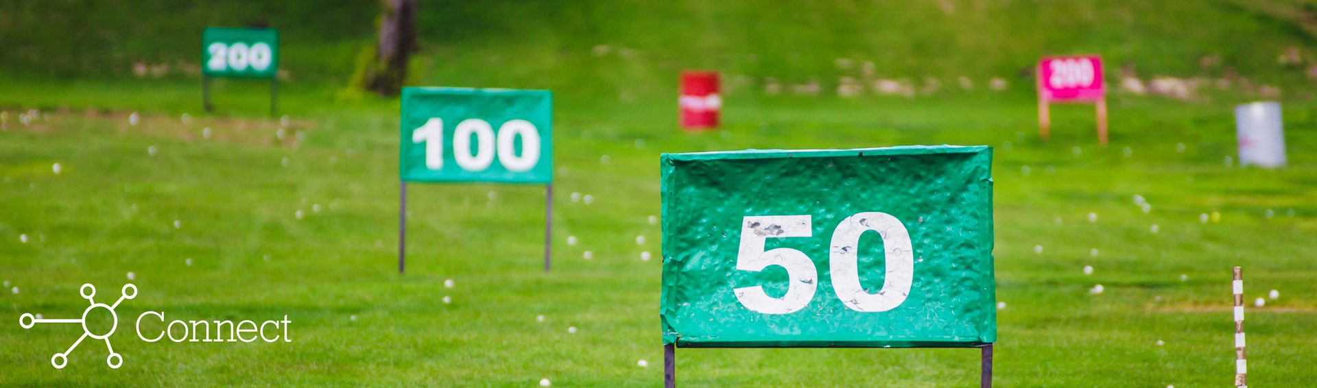 Distance markers laid out on a driving range with golf balls strewn across the grass