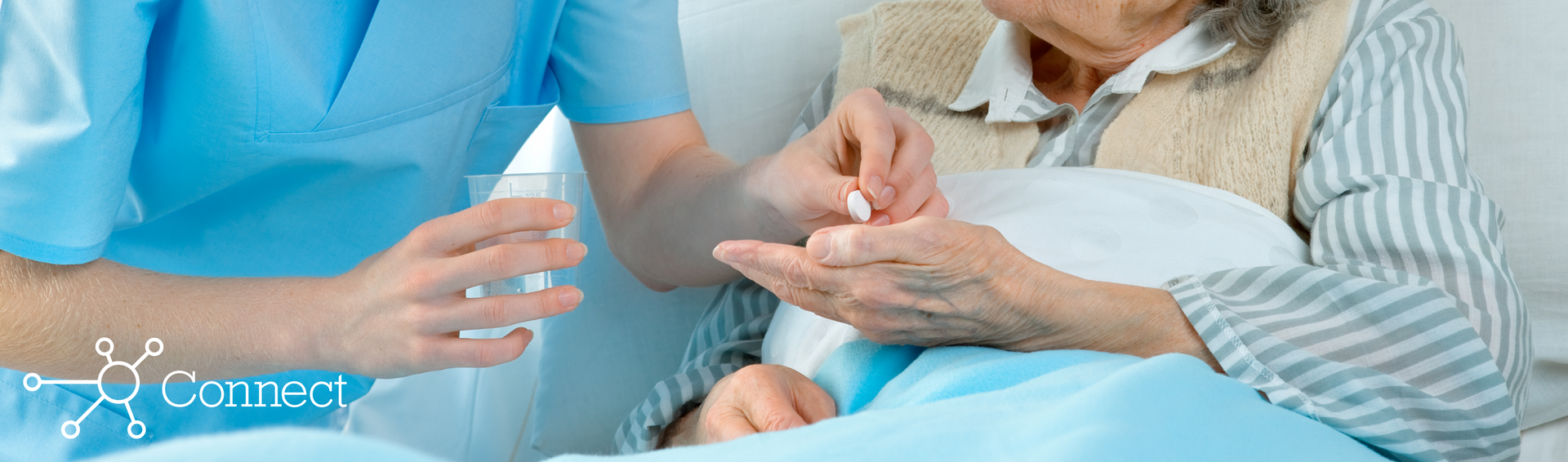 A female nurse handing medication to a woman laying in a hospital bed