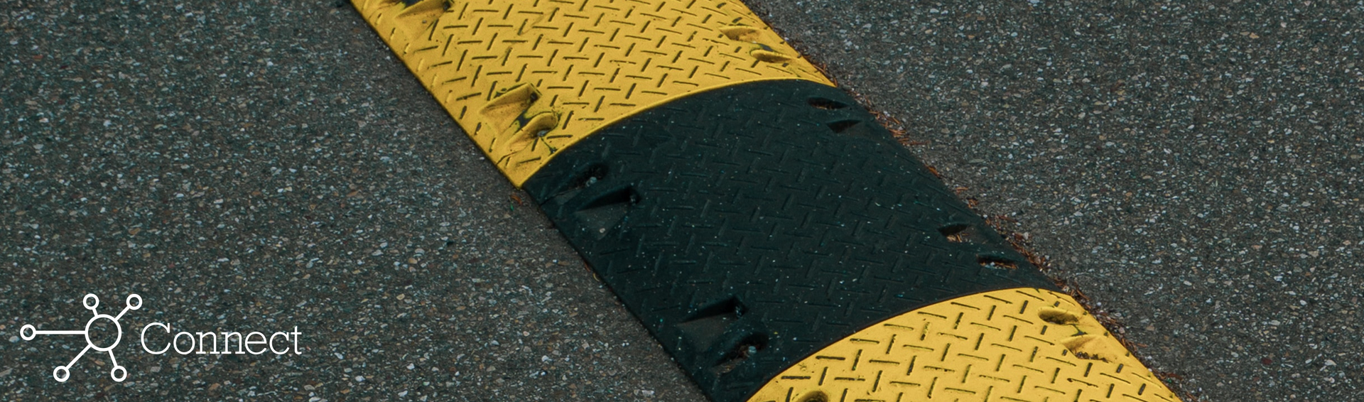 A yellow and black striped speed bump on asphalt