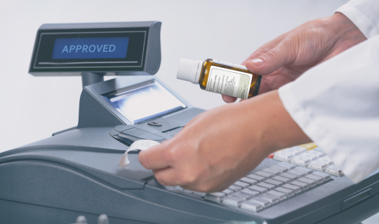 A pharmacist ringing up a prescription at a cash register