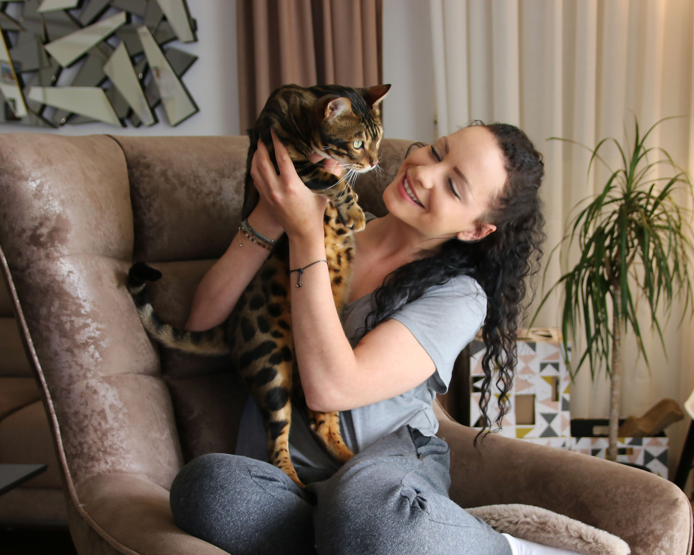 A woman sitting in a comfortable chair holding up her cat
