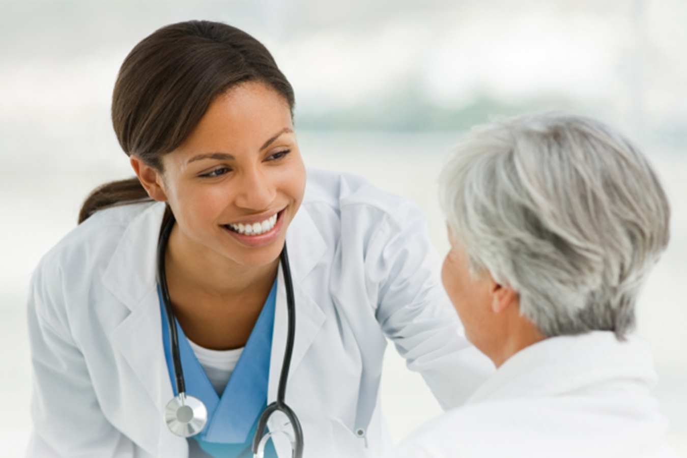 Nurse smiling down to a sitting senior patient