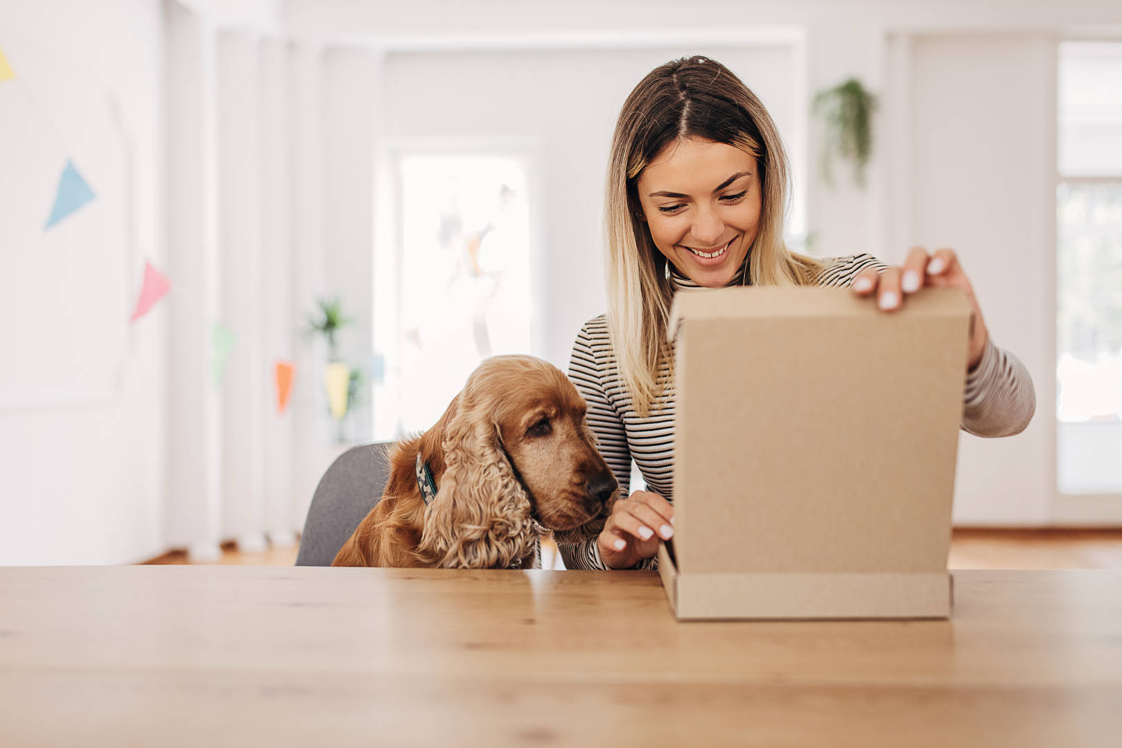 Woman opens package as dog looks on