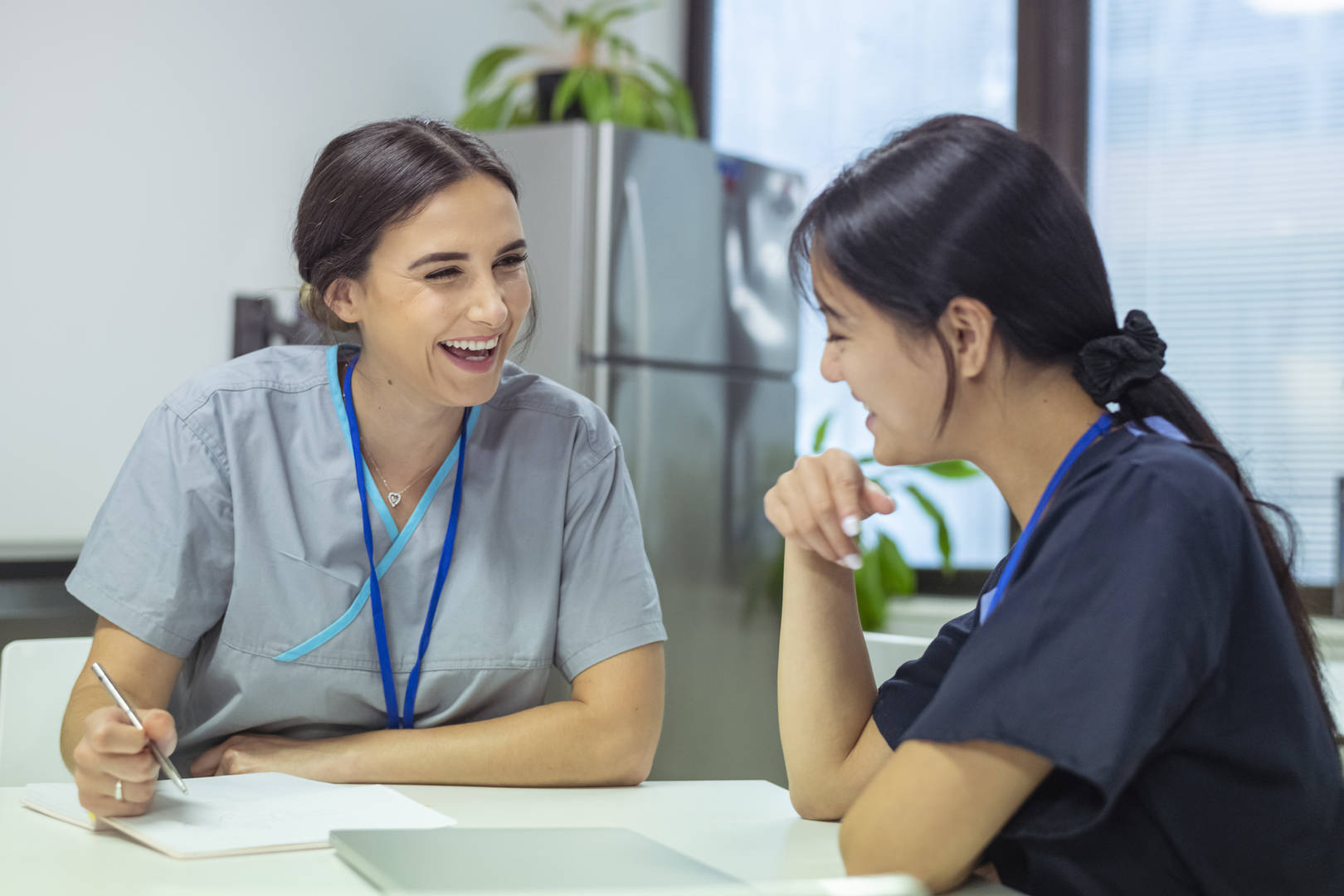 Two yoiung women in scrubs talk and laugh