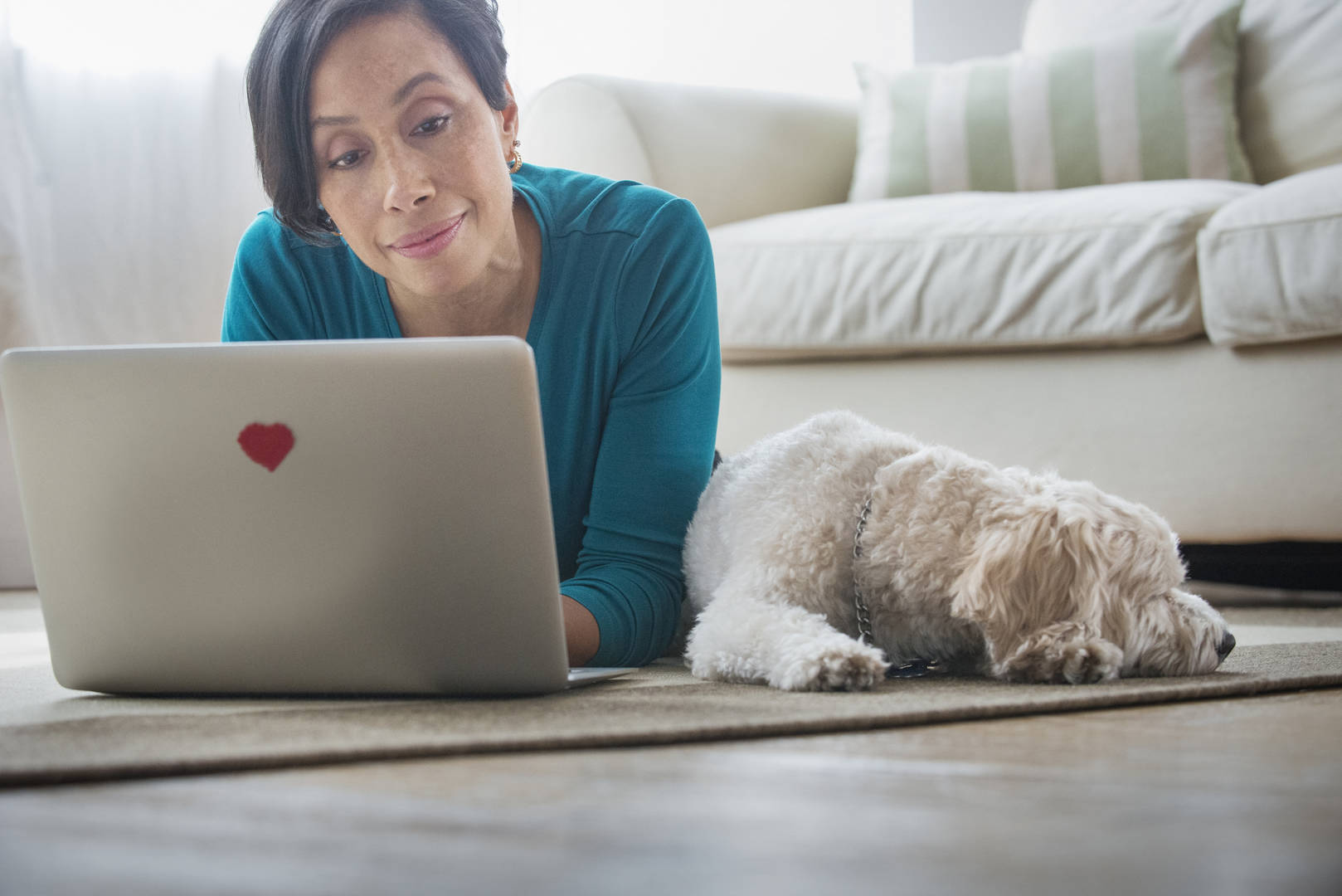 Black woman looks at laptop with small dog by her side