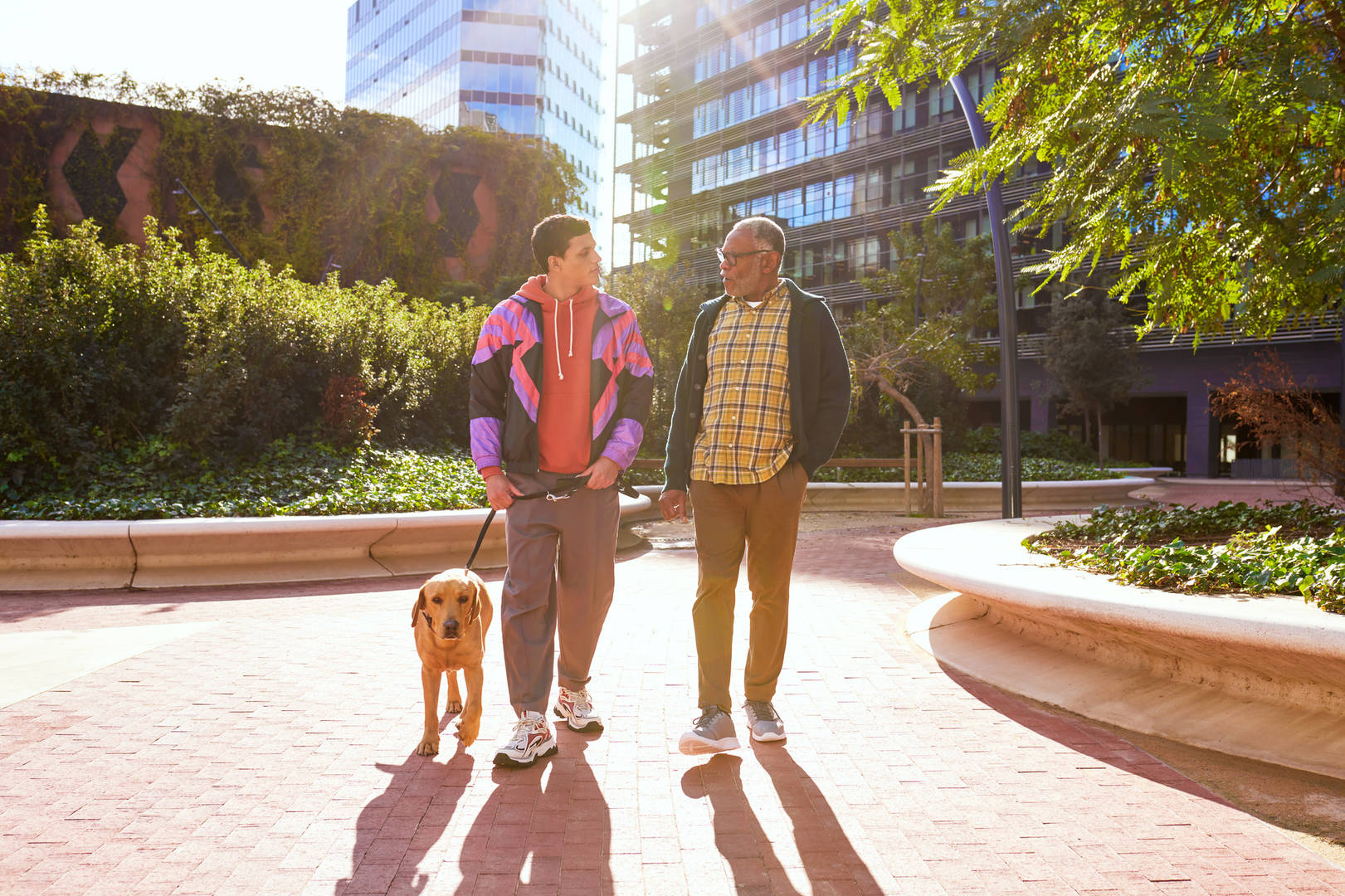 2 Black men walk a labrador retriever outside