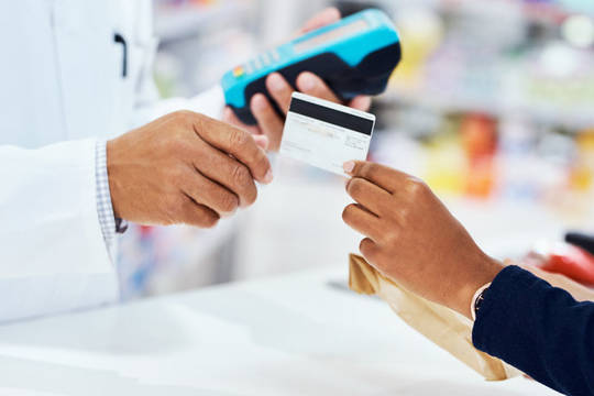 Hand giving copay card to pharmacist