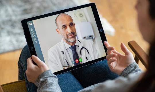 Male doctor speaking to patient on a tablet