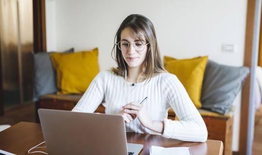 a young woman looks at a computer while at home