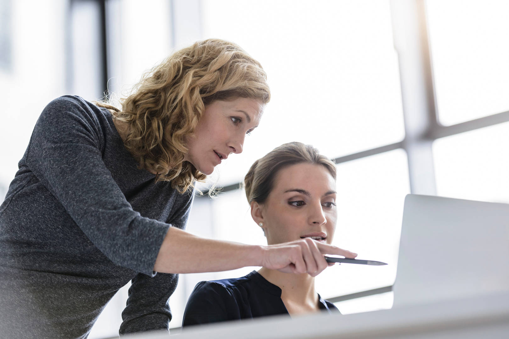 Two women having discussion in front of computer monitor